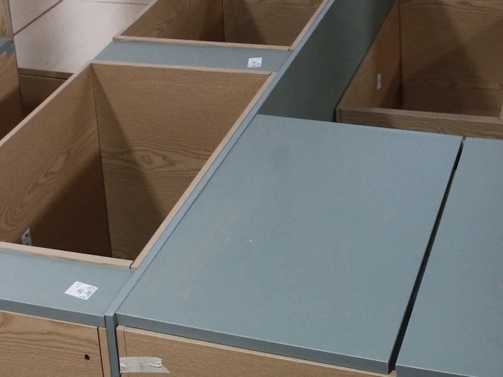 Oak-veneer cabinet carcasses with grey tops trial-assembled on the factory floor before flat-packing