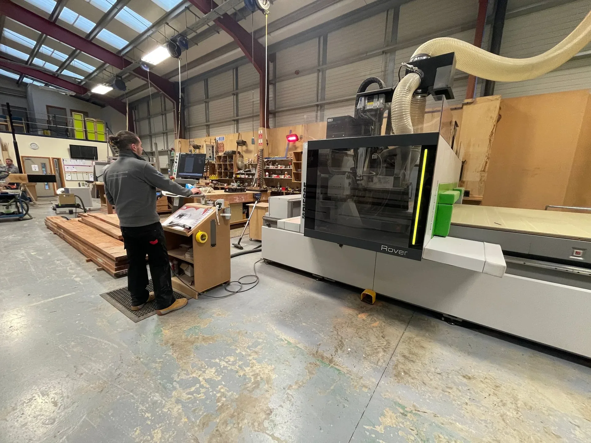 A CNC machining centre working a panel in a cabinet workshop, with an operator at the control station