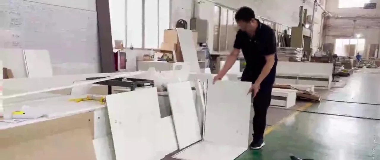 Assembler fitting cabinet panels during trial assembly in the factory assembly hall