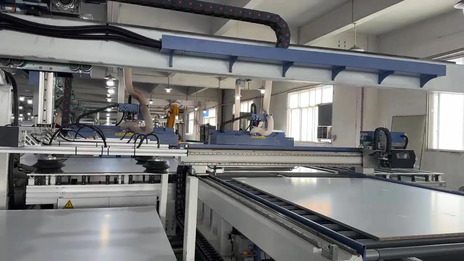 Panels moving through a cutting and edge banding line inside a cabinet factory