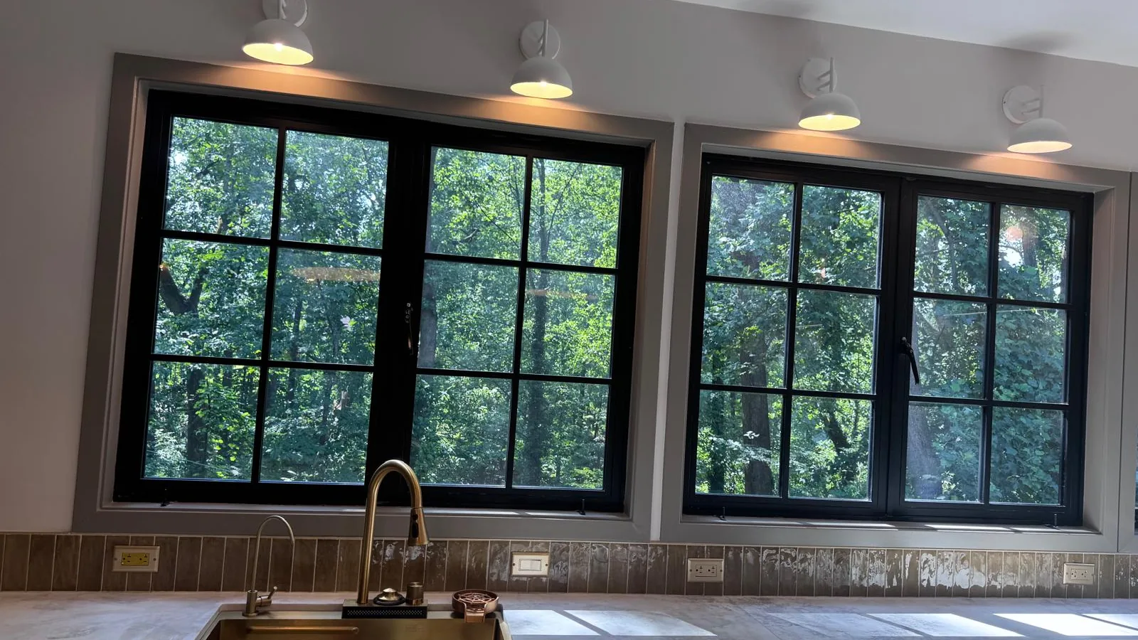 Kitchen counter run with brass sink and tap under black-framed windows