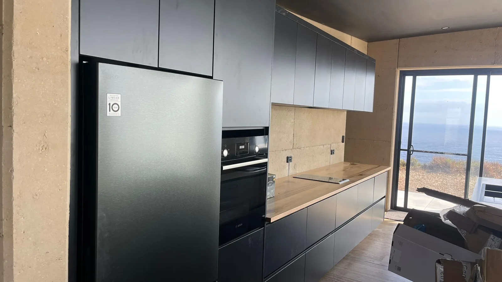Tall unit housing a fridge with pale upper cabinets