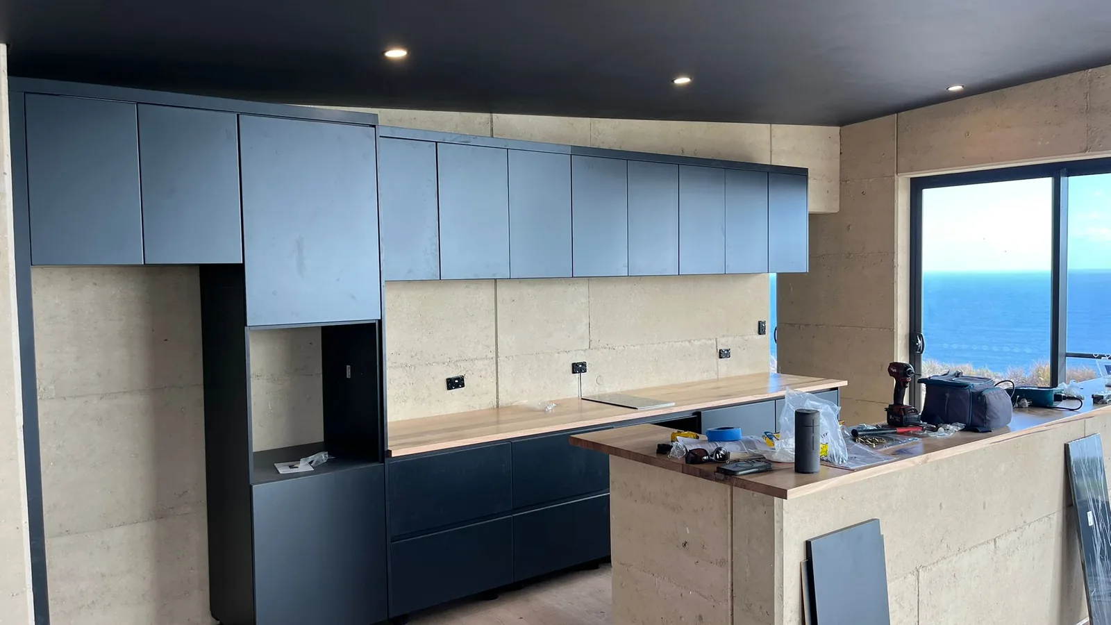 Kitchen island in dark lacquer with pale upper cabinets and sea view