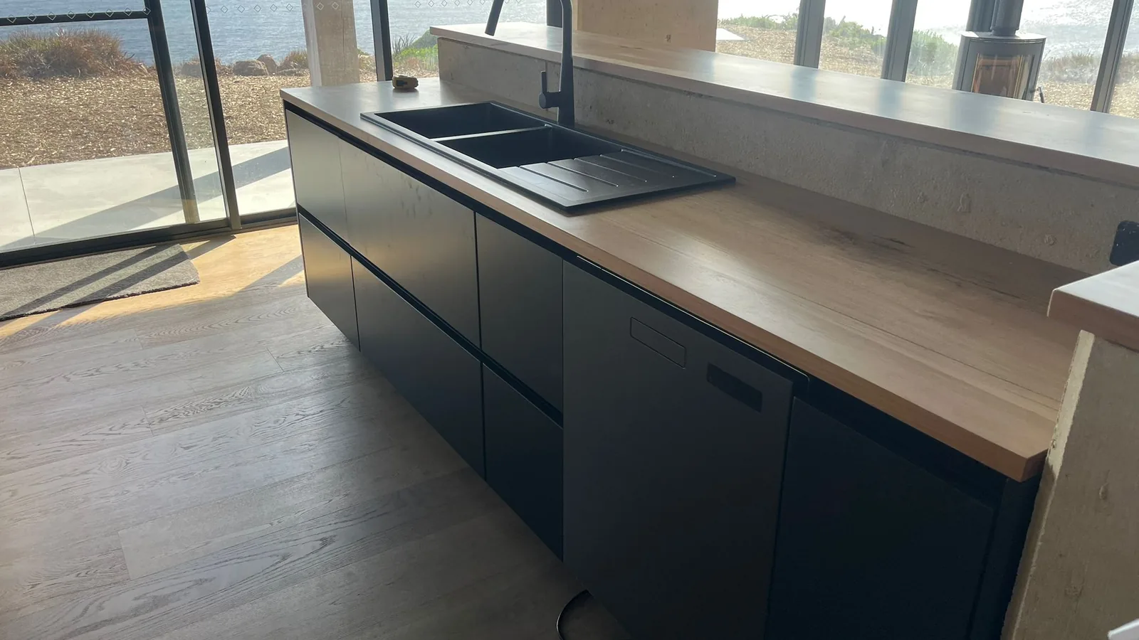 Kitchen sink run in dark lacquer with a full-height stone splashback