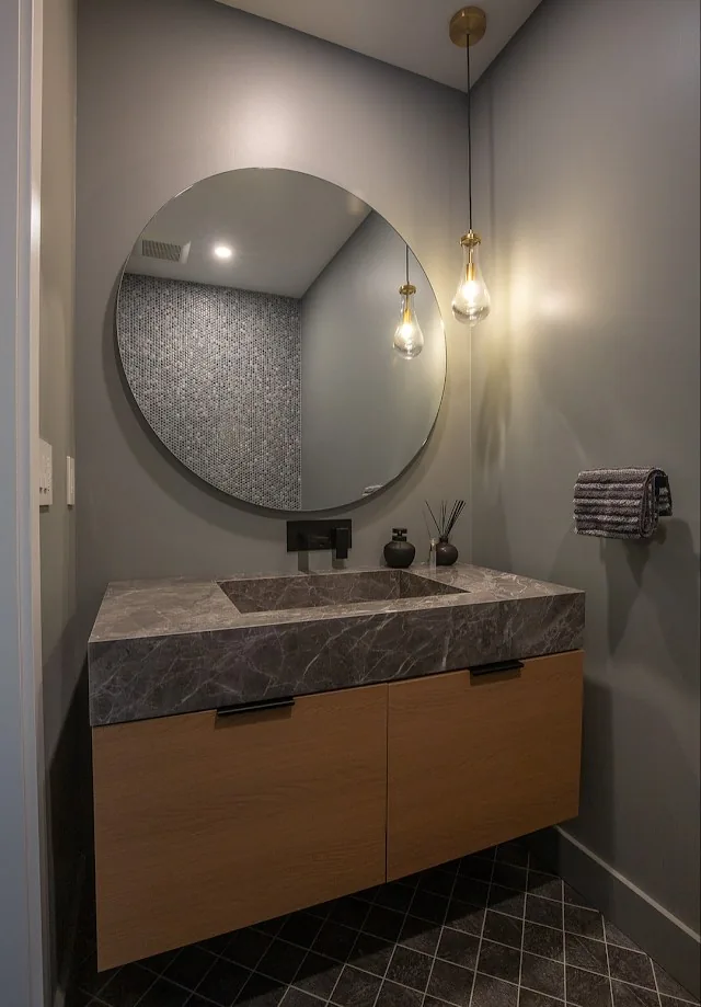 Powder room with round mirror and wood vanity, UK