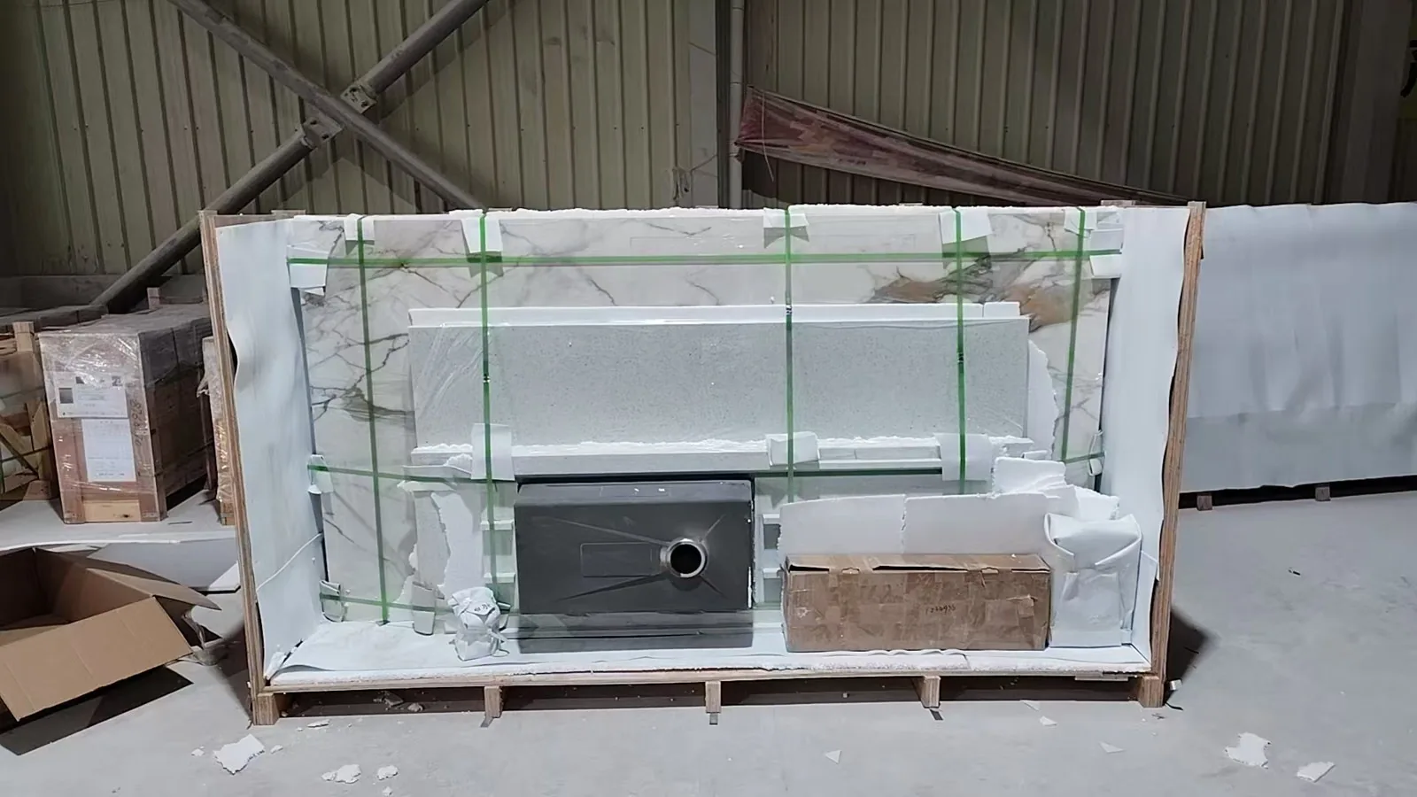Stone countertop, sink cut-out and hardware carton banded onto a pallet on the factory floor, wrapped and braced for export