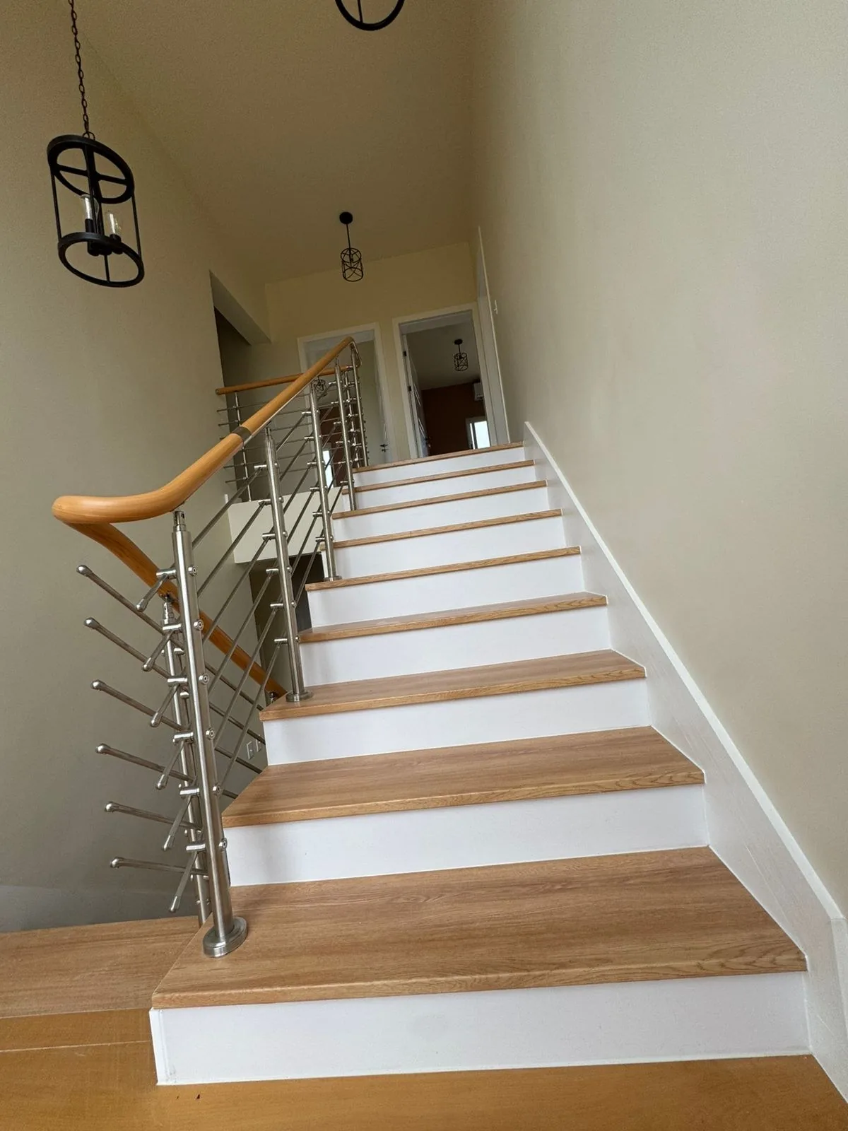 Wood-tread staircase with black metal rail and pendants