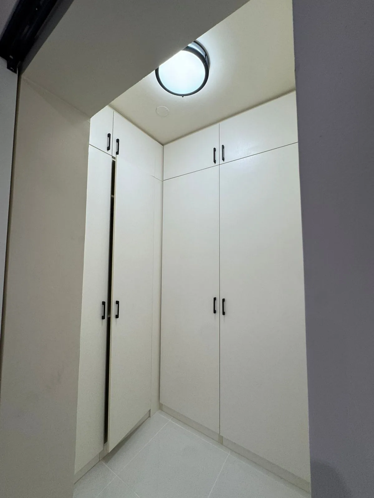 Walk-in with white tall cabinets under a round light