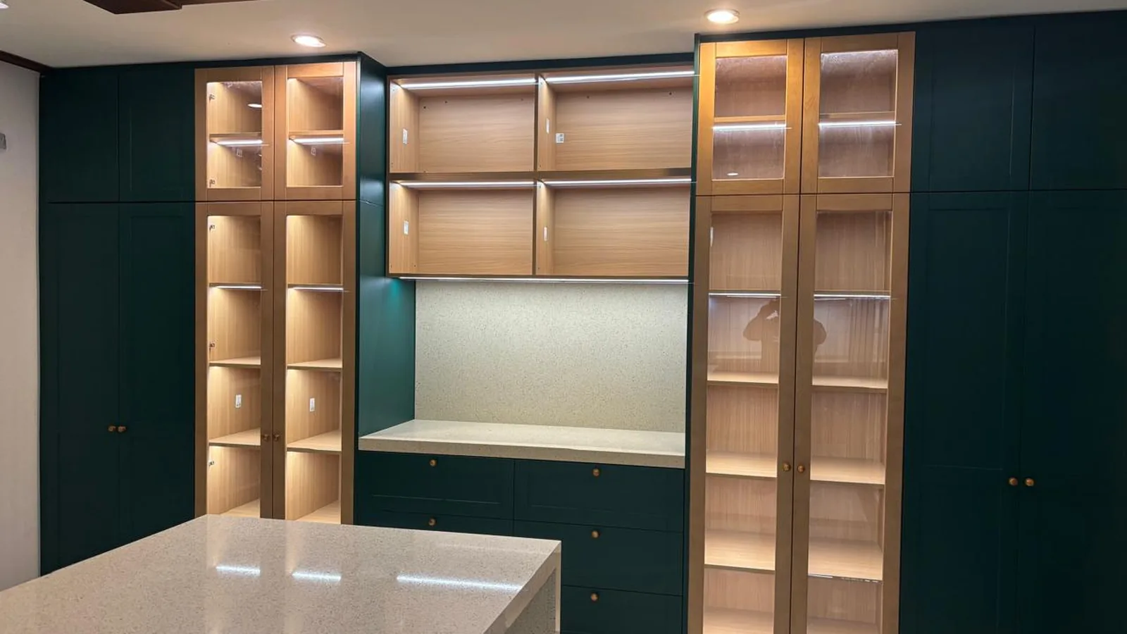 Green kitchen wall run with open shelving and a tall pantry