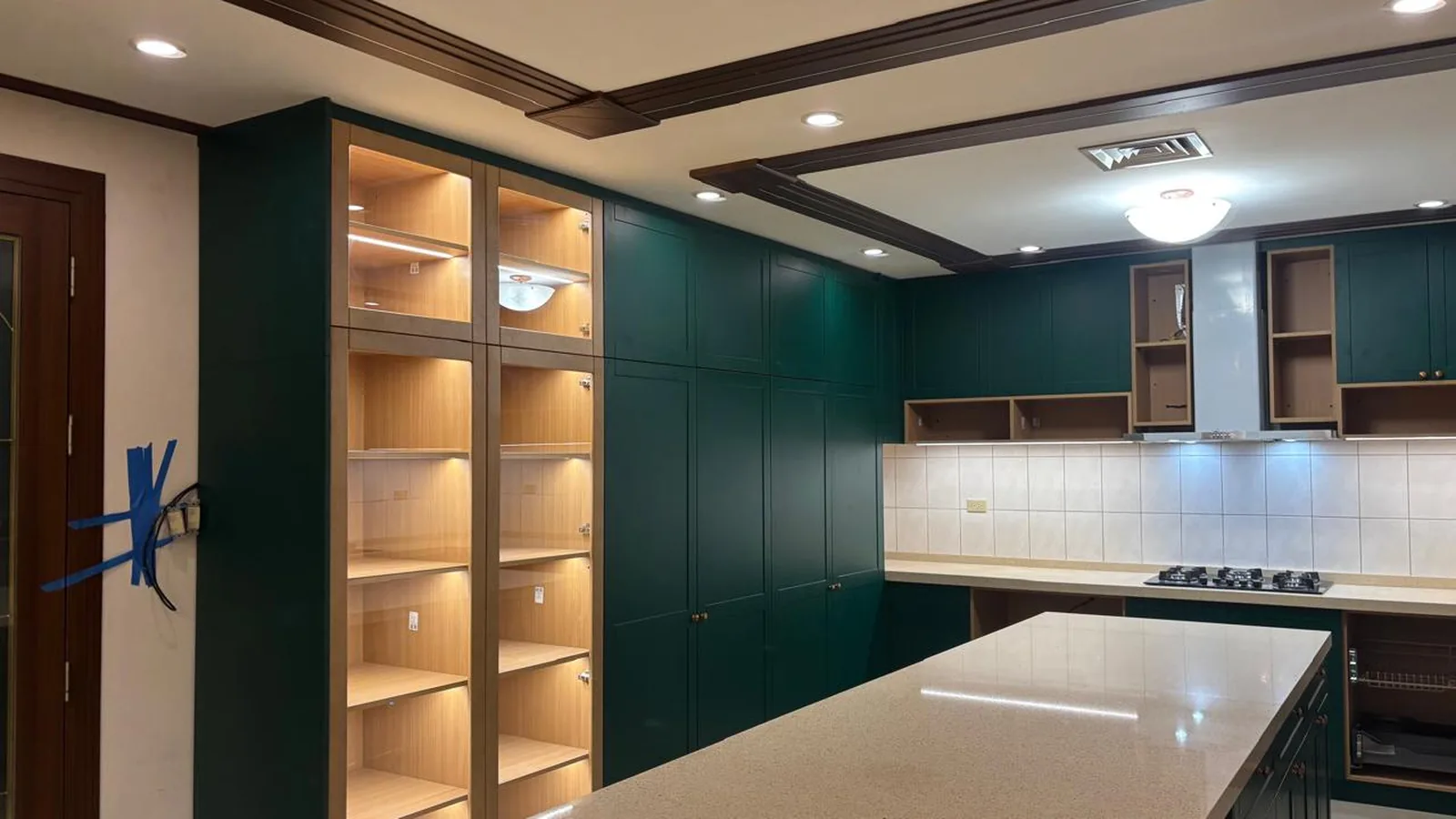 Tall green cabinetry with pale timber open shelving