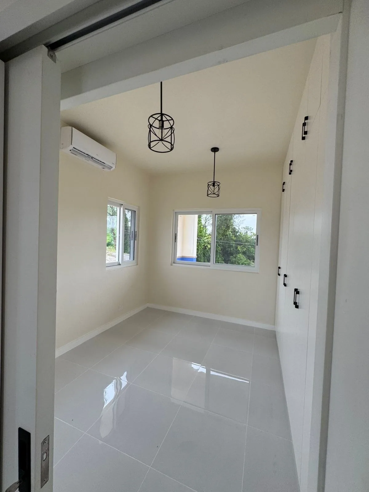 White living room with pendant lights and full windows