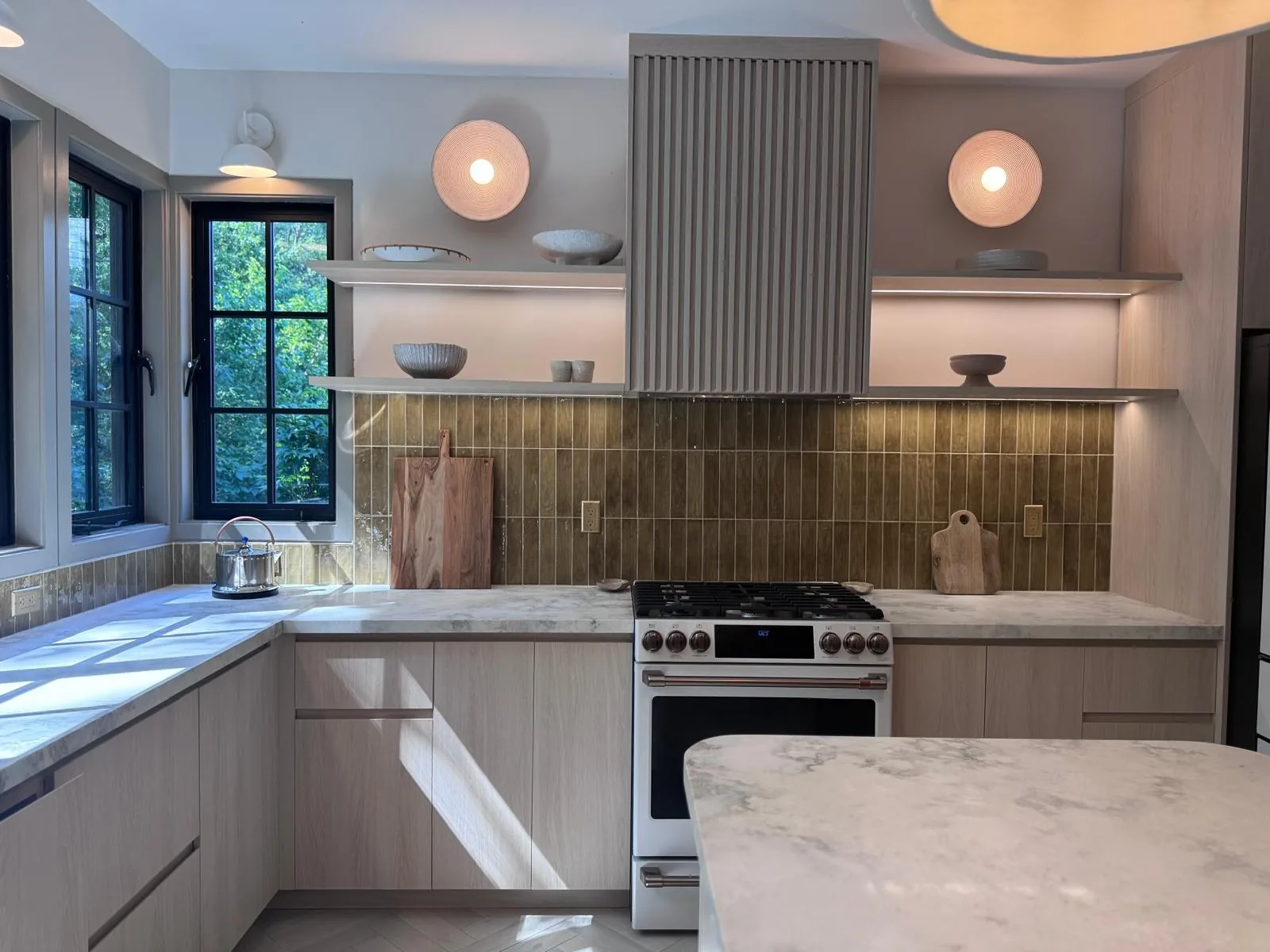 Kitchen with stone backsplash, range and round mirrors