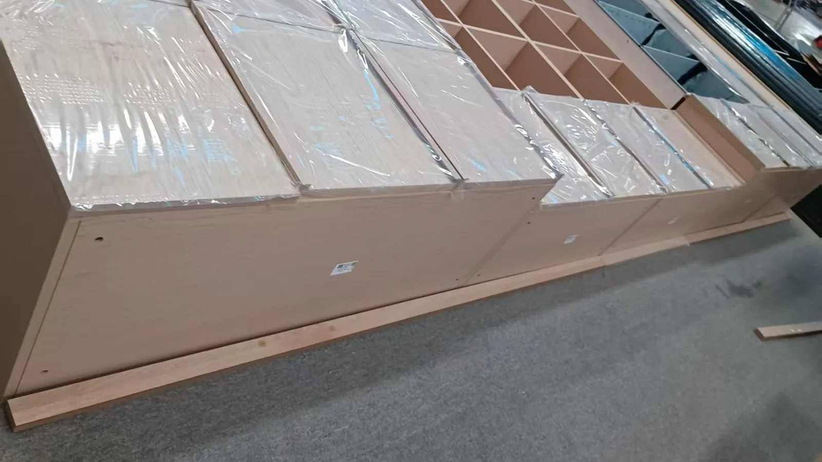 Oak-veneered cabinet carcasses wrapped and staged on the workshop floor