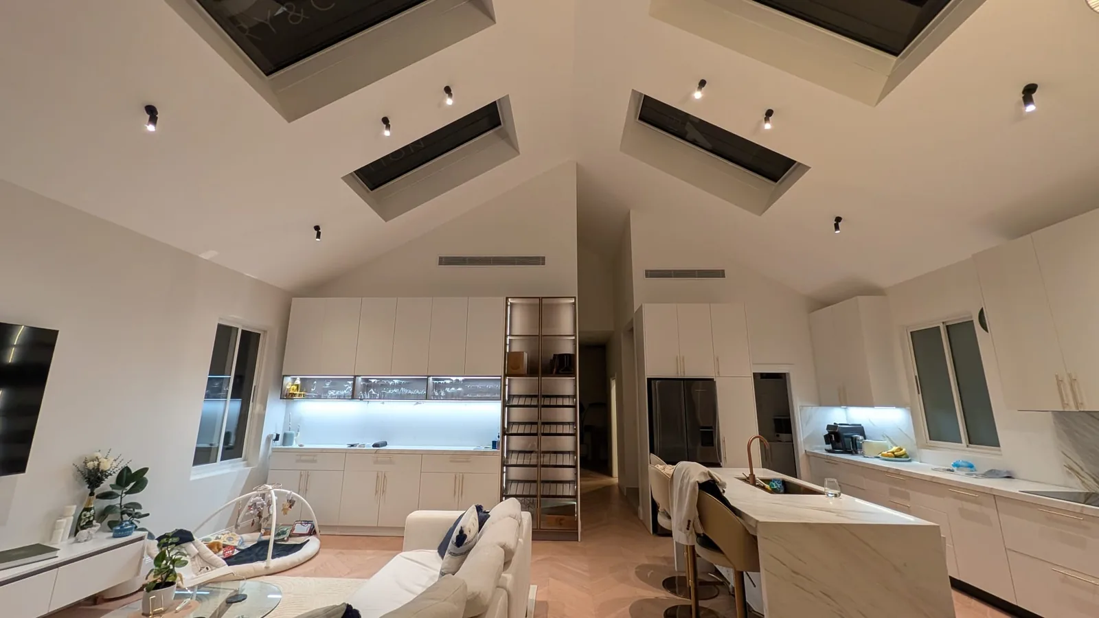 White kitchen under a vaulted ceiling with two skylights, Australia