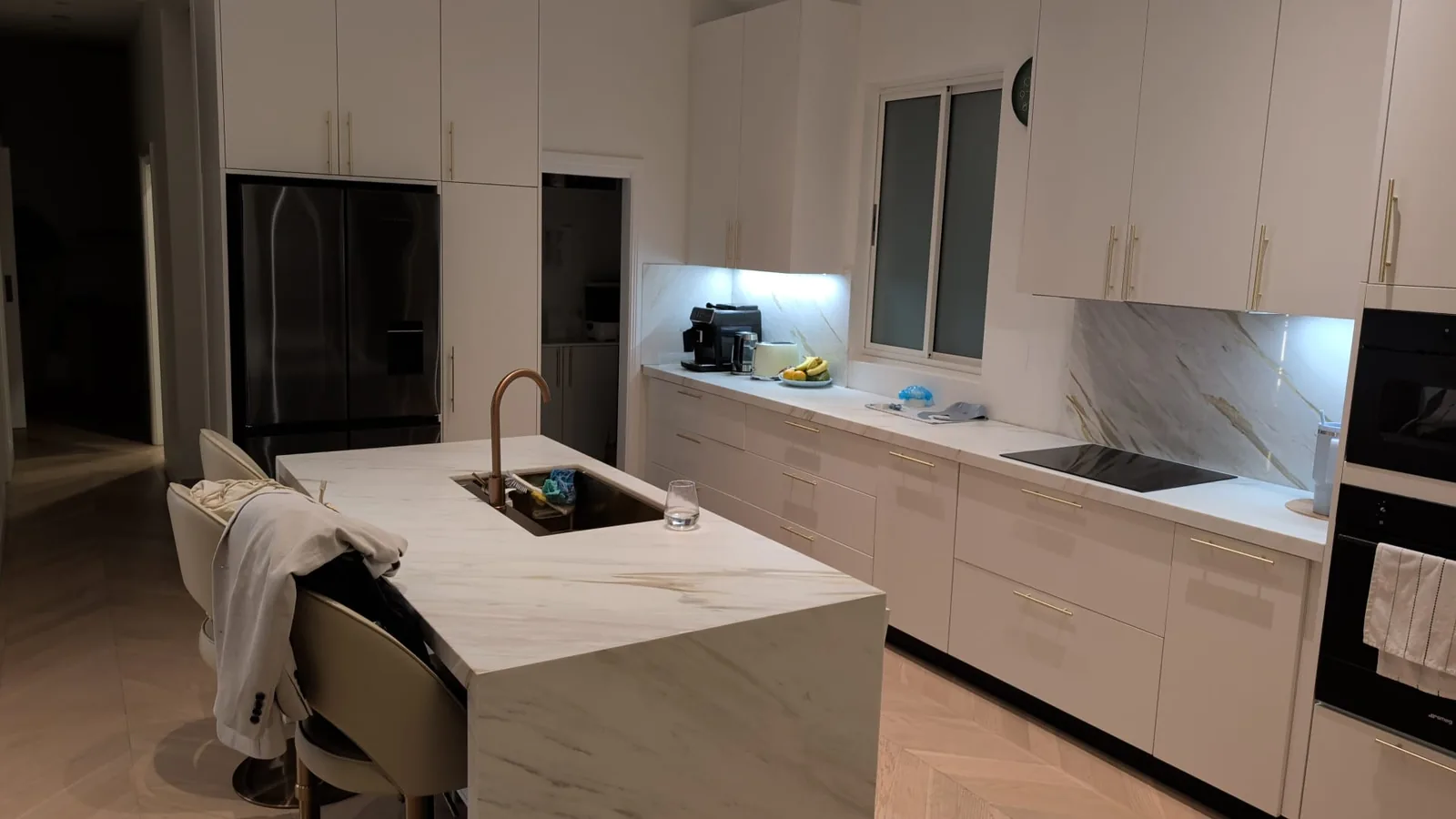 White flat-lacquer kitchen with marble island and stone splashback