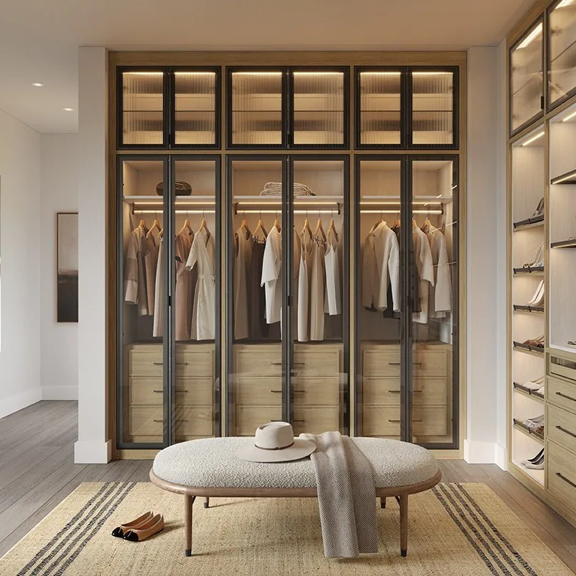 Floor-to-ceiling glass-front wardrobe wall with LED lighting and a settee