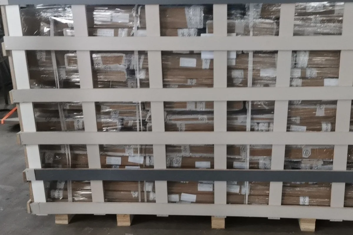 Flat-packed panel bundles strapped in a wooden crate frame, ready for the container