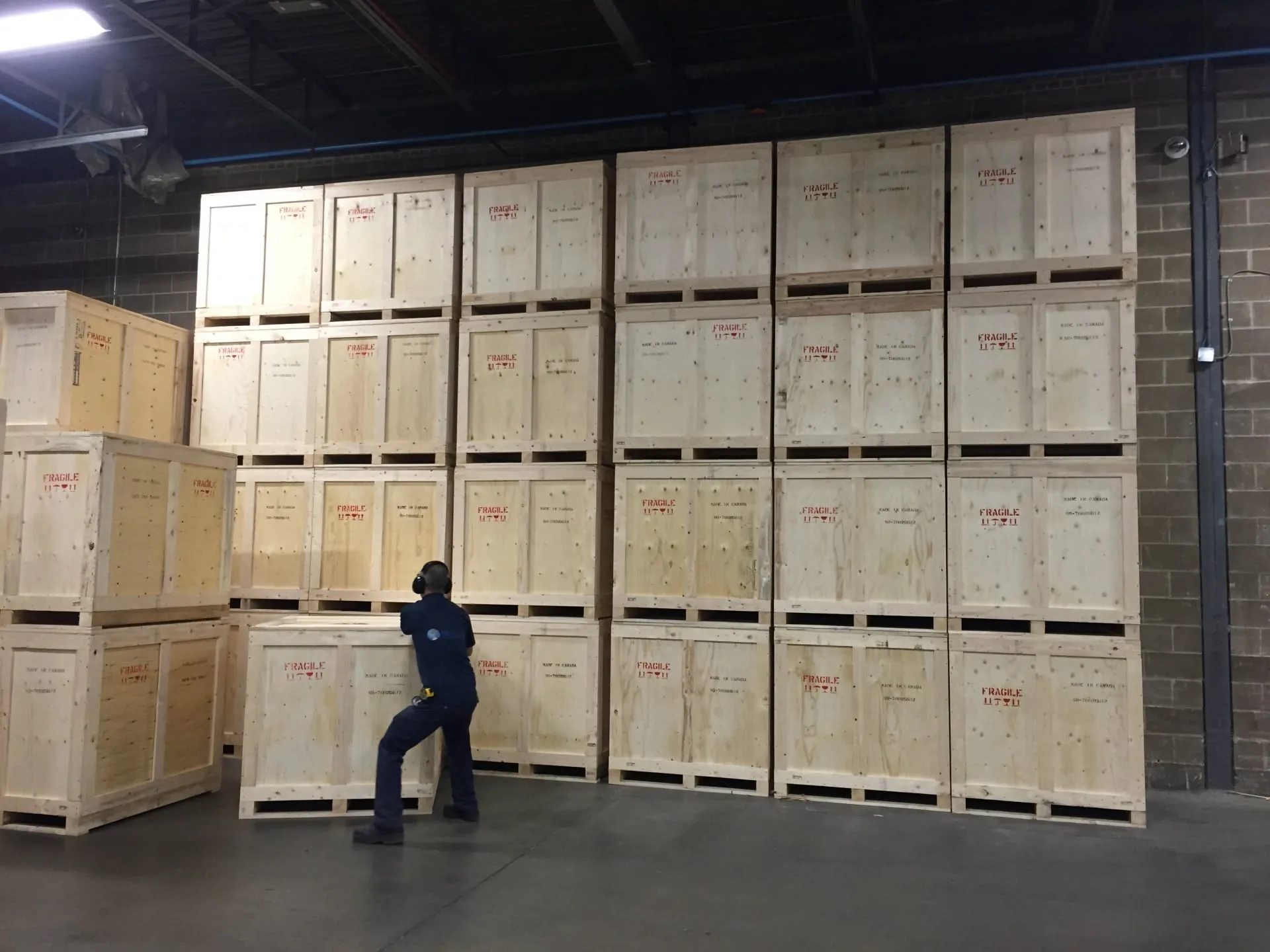 Crated cabinet components stacked in a warehouse, each crate stencilled FRAGILE, MADE IN CHINA and USE NO HOOKS