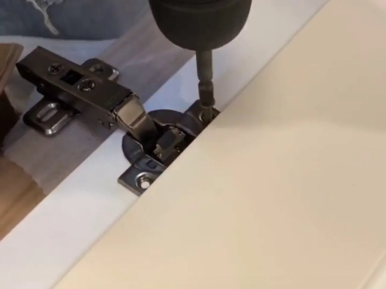 Soft-close hinge being fitted to a door-ready carcass - factory installation video frame