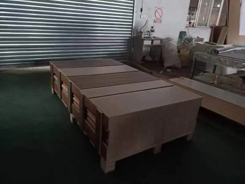 Flat-packed cabinet crates stacked on a workshop floor, taped and braced, ready for loading