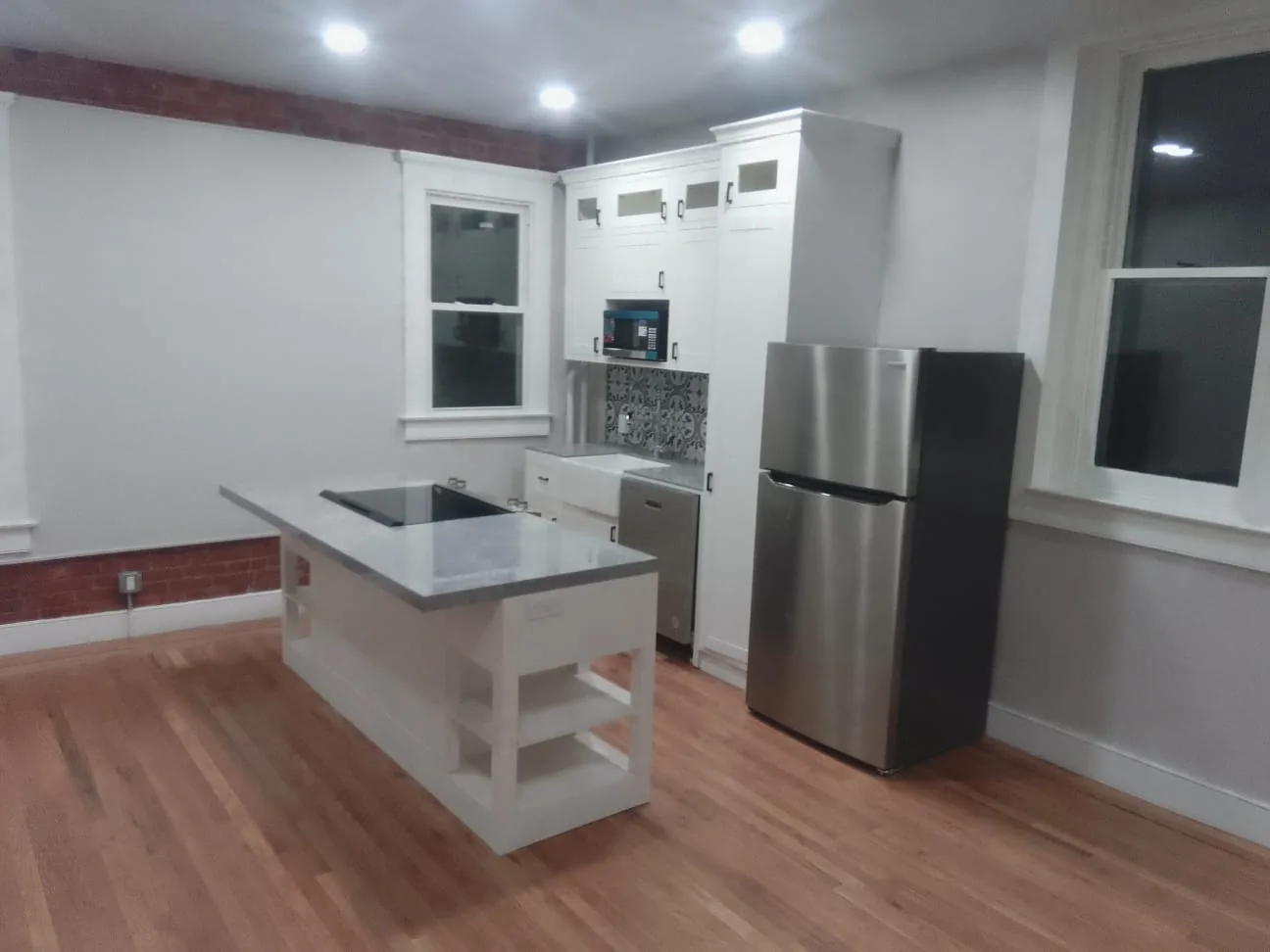 A fully replaced US kitchen with made-to-order white shaker base and wall cabinets, quartz counter and a farmhouse sink