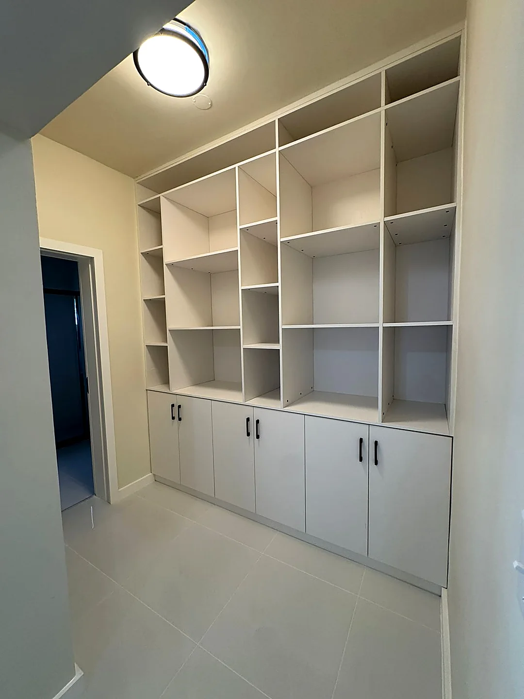 Floor-to-ceiling white built-in shelving over a lower cabinet run in a delivered villa