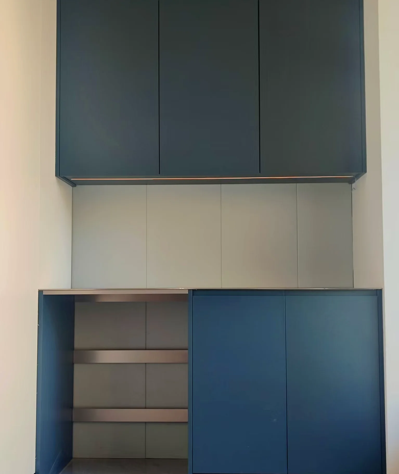 Handleless cabinet with the doors open, showing drawer boxes and adjustable shelving.