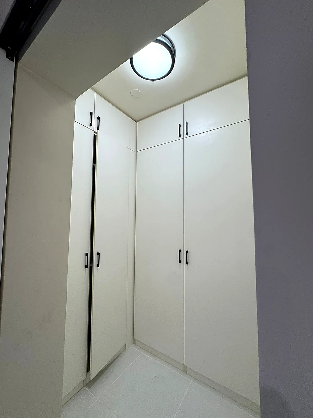 Four-door white walk-in closet in a corner of a delivered villa, full height to the ceiling